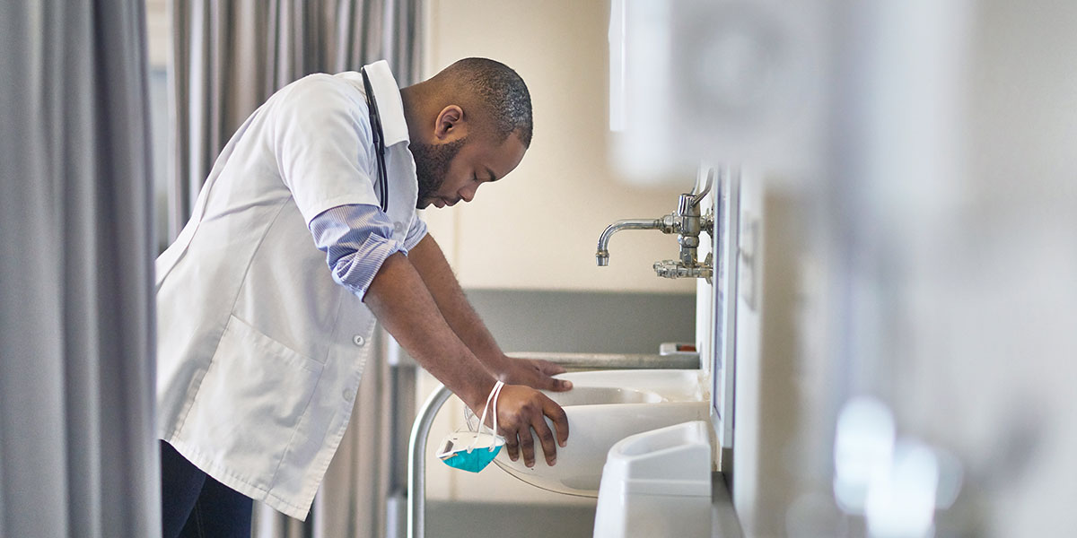 Tensed doctor leaning over sink in hospital