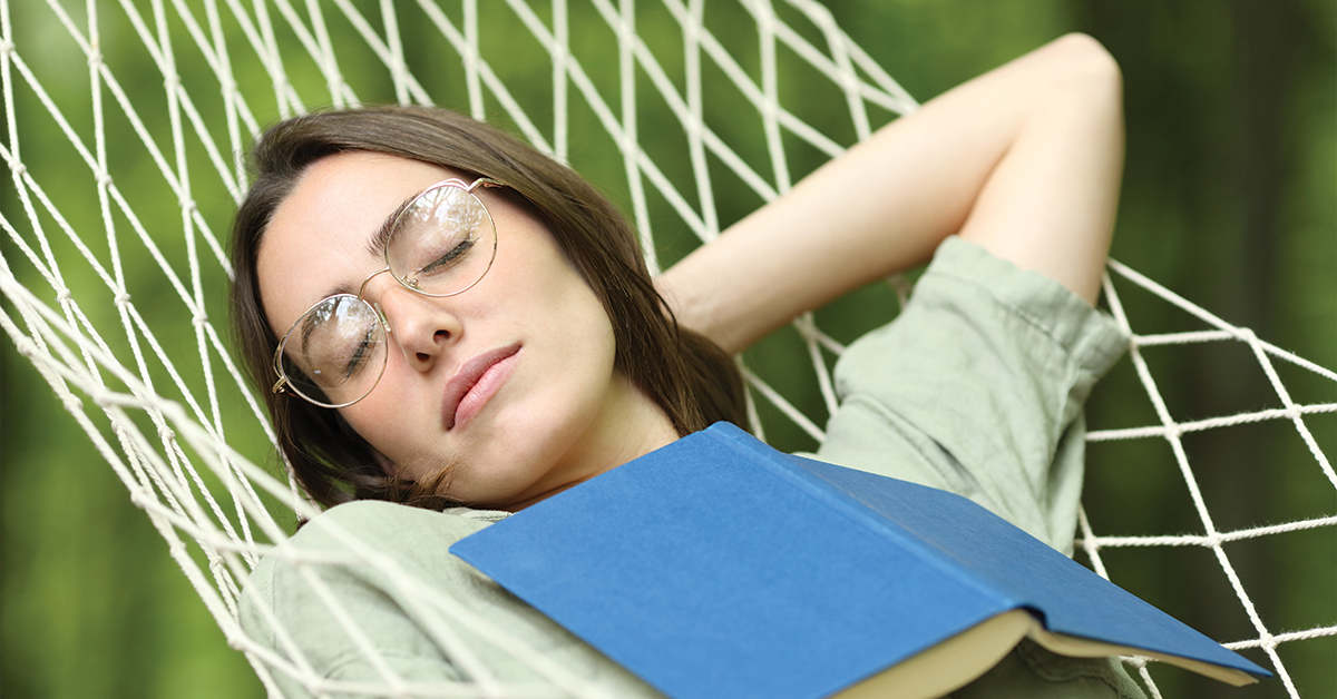 Woman sleeping on hammock with a book