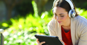 Woman wearing headphones watching media on tablet in a park