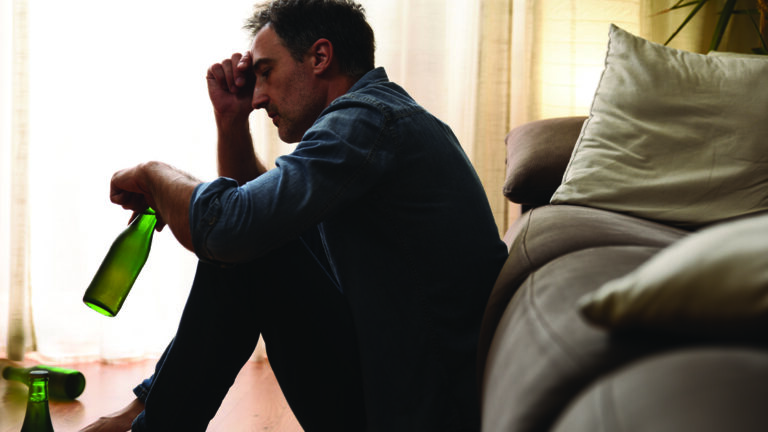 Alcohol or Drugs – Getting Help Sad man sitting in the living room drinking alcohol