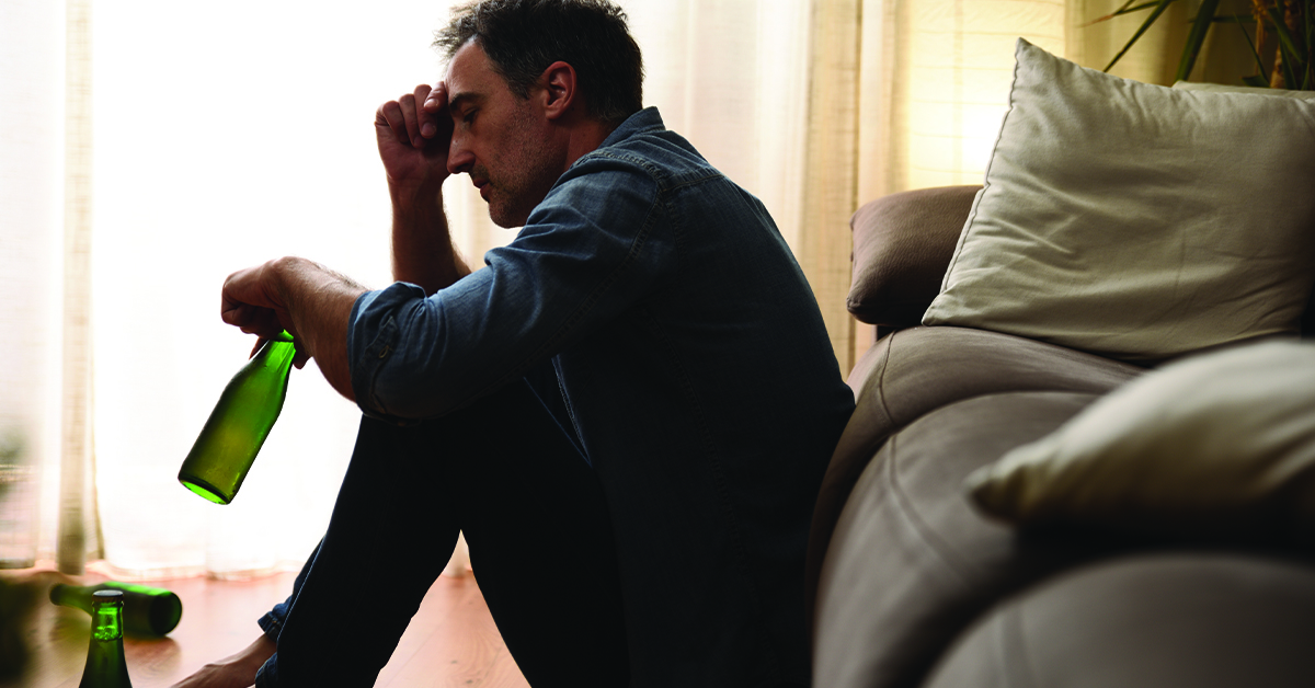 Sad man sitting in the living room drinking alcohol