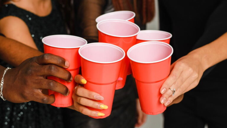 Featured Blog Image – Cutting Back or Quitting Alcohol Use Waist up of six friends having fun and drinking alcohol during New Year party, isolated on white background. A group of cheerful friends of different nationalities clink glasses with red glasses at a party in the studio.