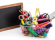 Shopping basket filled with school supplies isolated on white background