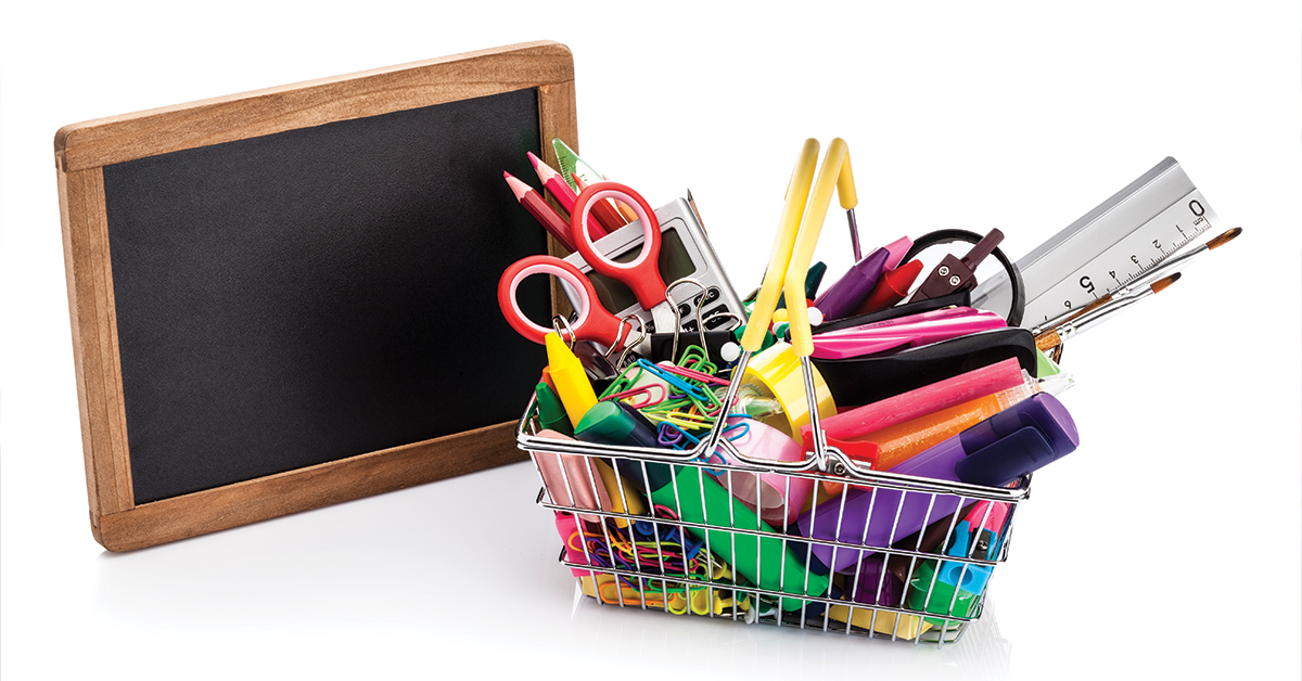 Shopping basket filled with school supplies isolated on white background