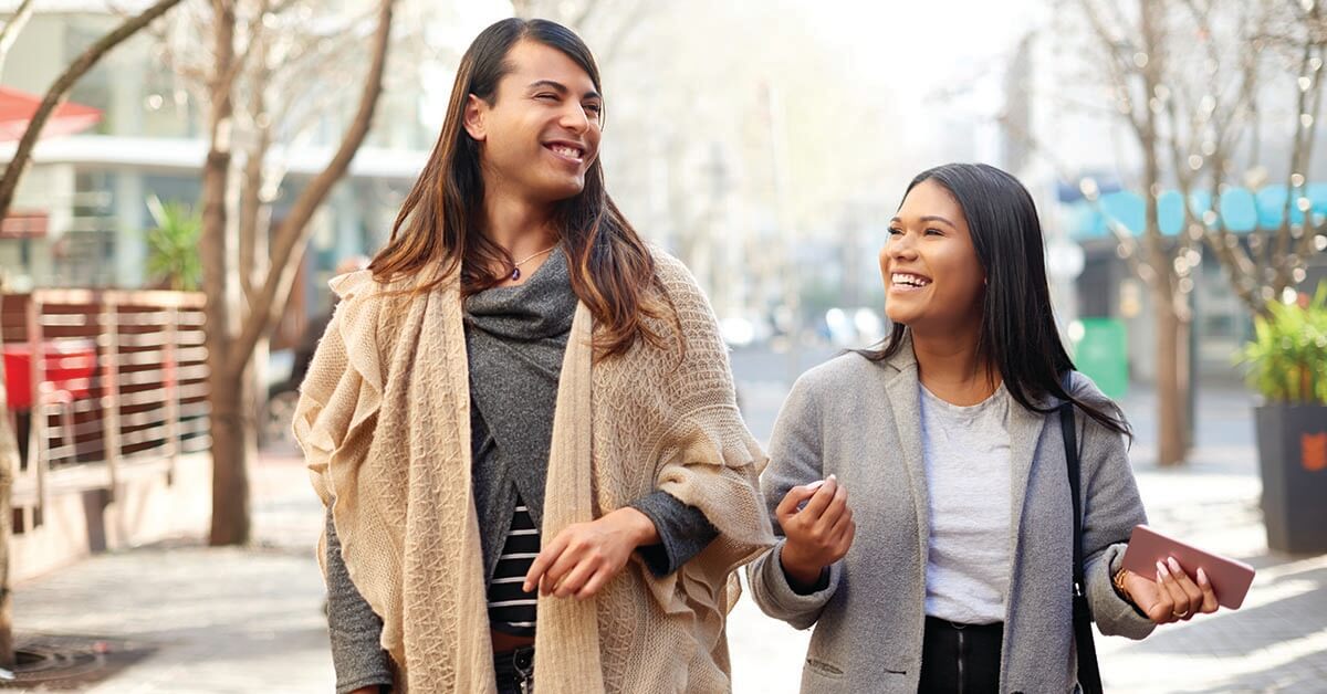 Cropped shot of two affectionate young friends having a discussion while walking in the city