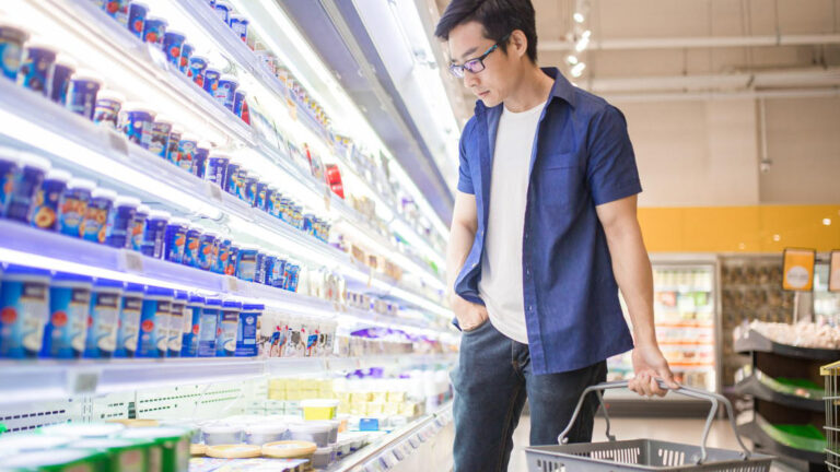 Blog Featured Image – Break Unhealthy Spending Habits A Chinese mature man holding basket and browses for products in the Frozen Goods Section.