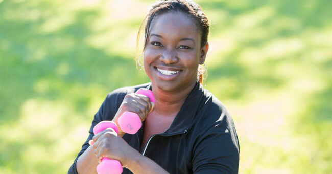 Blog Featured Image – Manage Stress with Exercise Mature African American woman (40s) in park, exercising with hand weights.