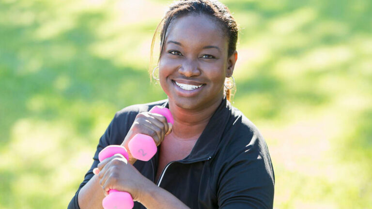 Blog Featured Image – Manage Stress with Exercise Mature African American woman (40s) in park, exercising with hand weights.