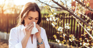 Attractive young adult woman coughing and sneezing outdoors. Sick people allergy or virus influenca concept.