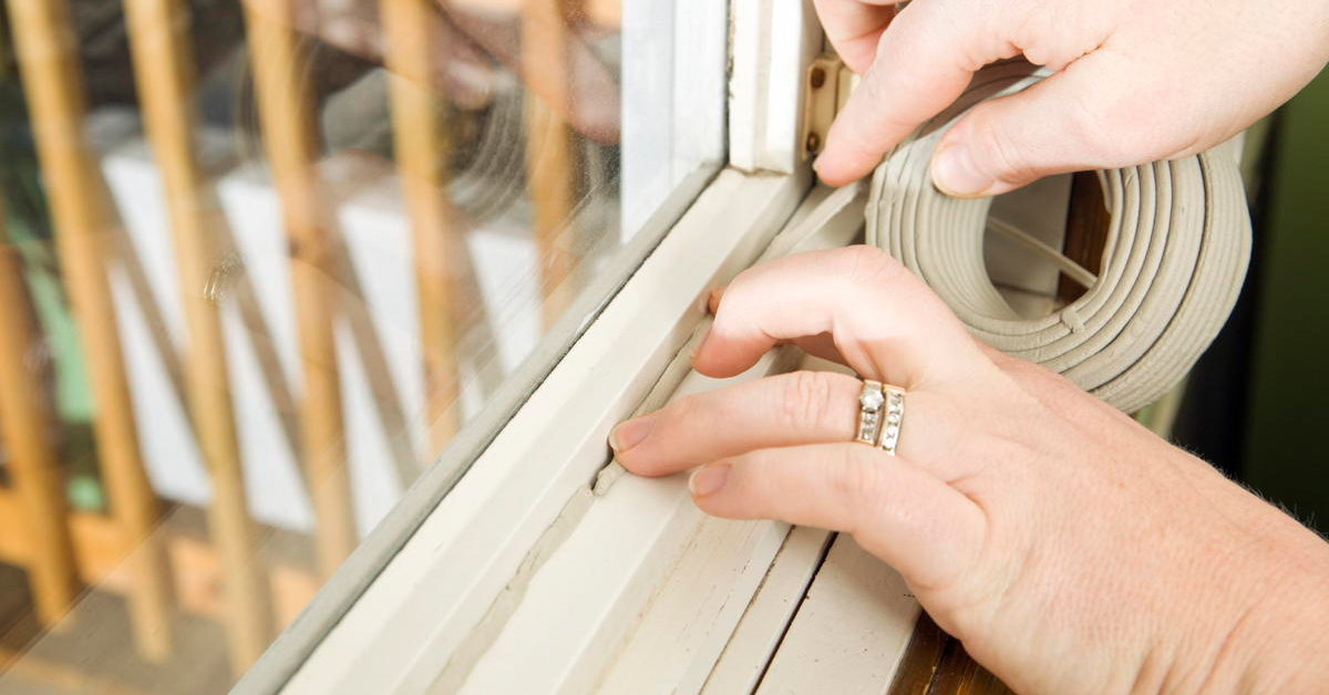 Blog Featured Image – Reduce Summer Cooling Costs Hands Applying Weather Seal Caulk to Window Frame
