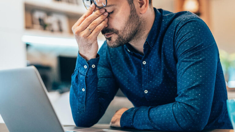 Blog Featured Image – Reframe Negatives by Building Resilience Tired young businessman working at home using lap top and looking Anxious