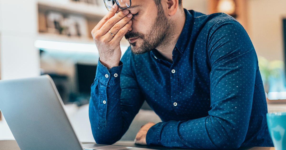Tired young businessman working at home using lap top and looking Anxious