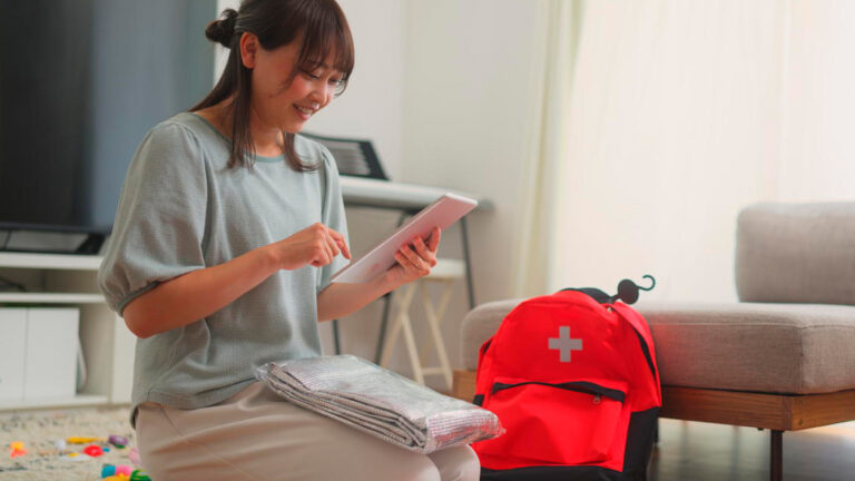 Blog Featured Image – Stay Prepared This Safety Month A woman is preparing an emergency bag in the living room at home.