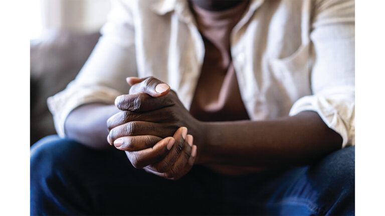 Coping with Trauma Close up of an unknown African-American man's claspling hands with the elbows leaning on his knees