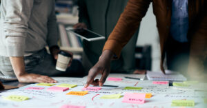 Close-up of creative people working on new business project and analyzing mind map on paperboard.