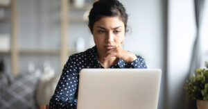 Serious frowning indian woman read email on laptop feels concerned