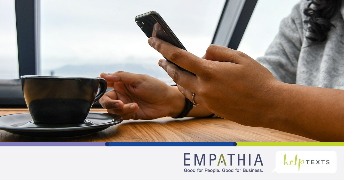 Person Holding Ceramic Cup on Table Typing on Cell Phone