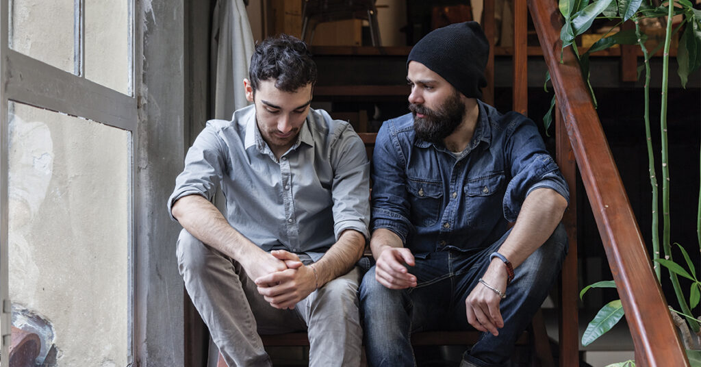 Couple of young men talking on the stairs of an office
