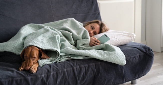 Episode 26 – Diagnosing Seasonal Affective Disorder with Therese Sorrentino, Part One Sad woman lying on sofa with dog, using smart phone in hands wait for boyfriend call or text, feels depressed. Thoughtful female think about relationships problems. Mental health, loneliness concept.