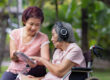 senior woman and daughter listening music with headphone in backyard