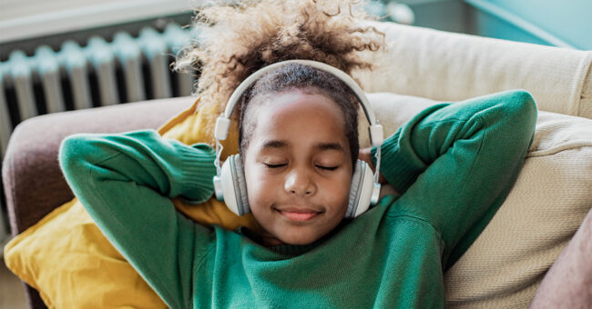 Featured Image – Podcast Episode 22 – The Unheard Benefits of Music Therapy with Nancy Dexter-Schabow, Part 1 Cute African girl is at home, she is using wireless headphones