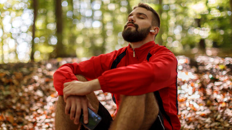 Featured Image – Self-Care During Election Season Portrait of relaxed young man with bluetooth headphones in forest