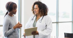 Female doctor and senior patient discuss medical records