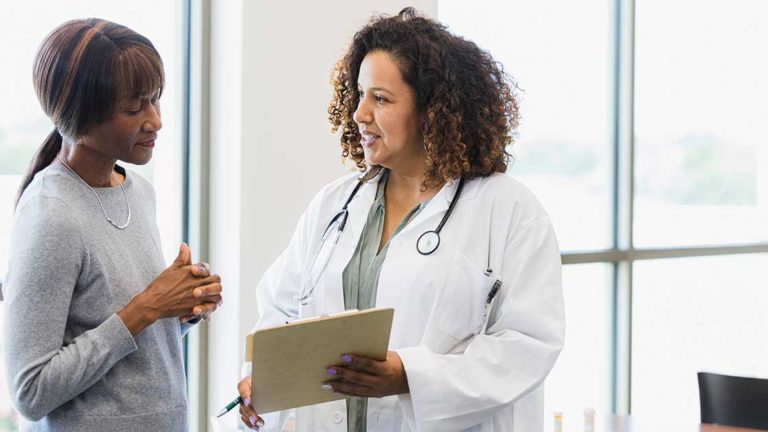 Female doctor and senior patient discuss medical records Female doctor and senior patient discuss medical records