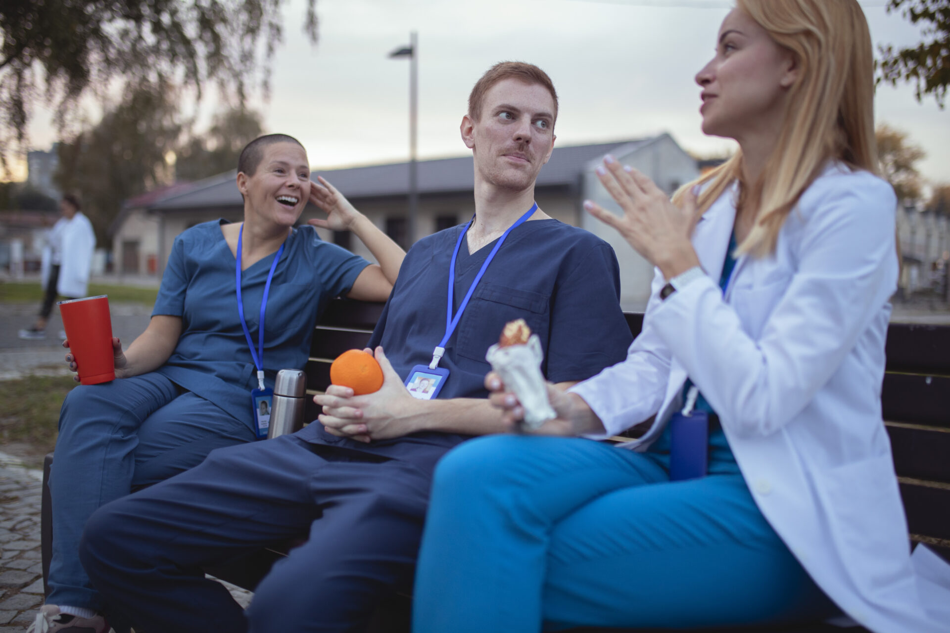 A small group of medical workers sits on a bench in the hospital yard and chats during a coffee break