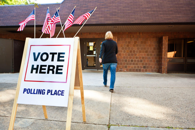 Woman Voter Entering Voting Polling Place for USA Government Election voting signage outside of polling building