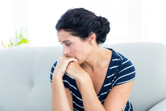 Unhappy woman sitting on the couch woman looking depressed on a couch