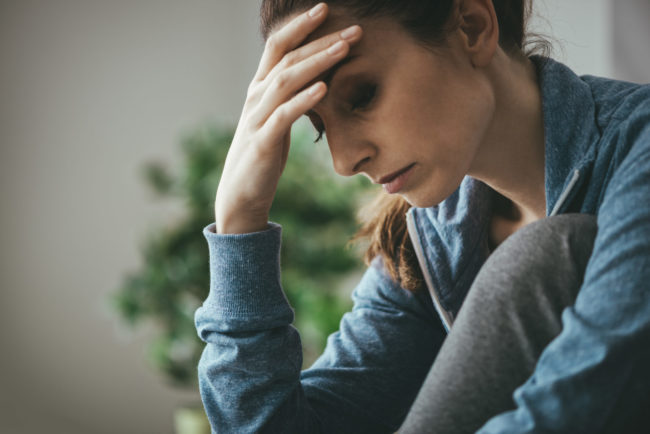 Depressed woman at home woman with hand on head looking sad