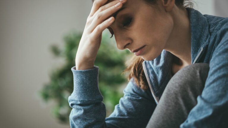 Depressed woman at home woman with hand on head looking sad