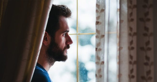 Grief-Depression-Holidays Young sad mad standing by the window