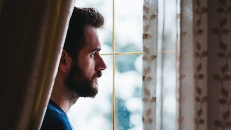 Grief-Depression-Holidays Young sad mad standing by the window