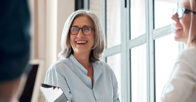 Happy mature old female mentor coach supervisor training young interns at group office meeting professional workshop. Happy mature old female mentor coach supervisor training young interns at group office meeting professional workshop.