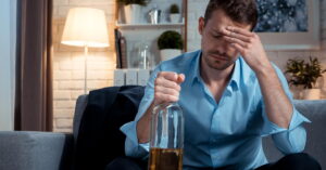 Worried businessman drinking alcohol at home