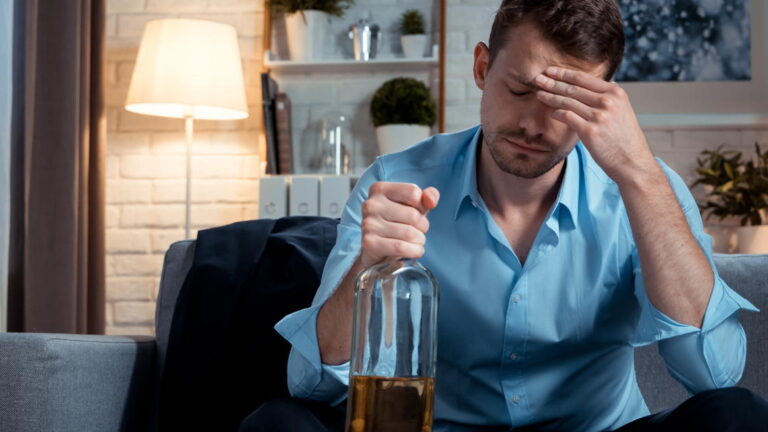 Worried businessman drinking alcohol at home