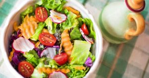 Healthy lunch bowl with greens, avocado, cherry tomatoes, radish