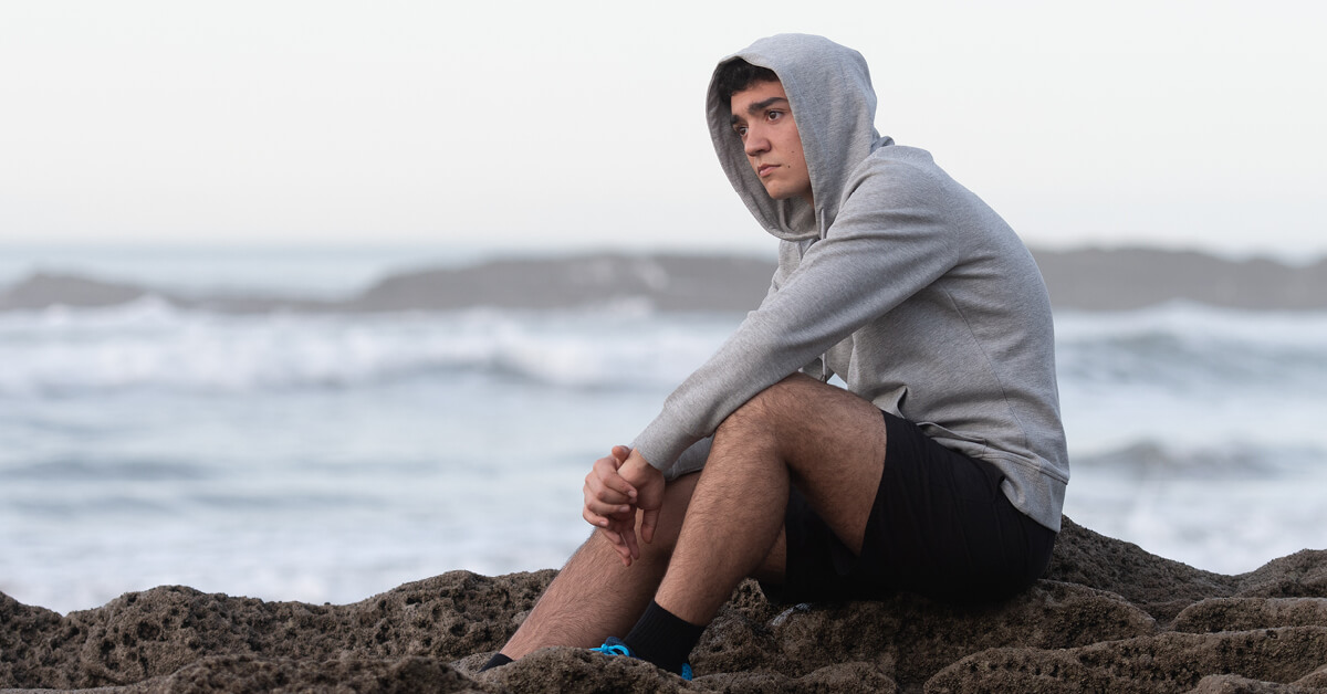 Sad teen sitting alone on beach