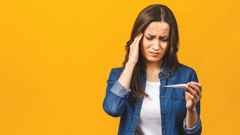 Preparing for Flu Season Young woman having flue taking thermometer. Isolated against yellow background. Beautiful young woman is sick with a high temperature, a thermometer, isolated close-up. Cold, flu concept.