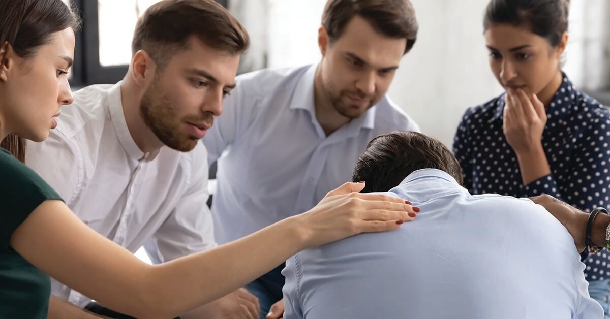 Diverse group giving comfort and support to upset mate