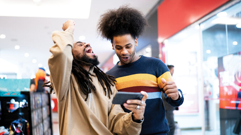 Responsible Gambling Brothers watching sports or playing on the smartphone at the mall
