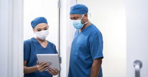 Healthcare coworkers walking and analyzing digital tablet at hospital - wearing face mask