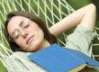 Woman sleeping on hammock with a book