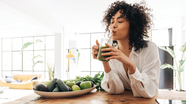 building-resilience-featured-image Young african american woman drinking green juice with reusable bamboo straw in loft apartment