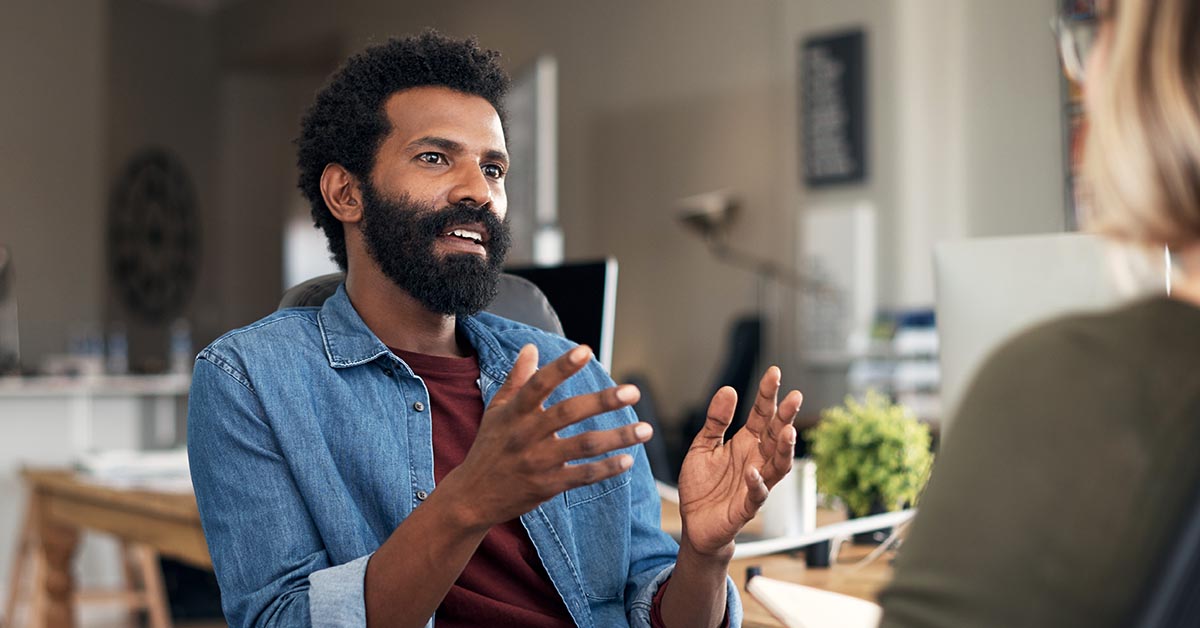 Shot of a young businessman having a discussion with his colleague in a modern office