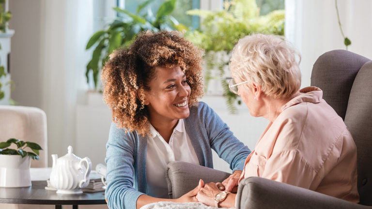 compassion-fatigue-featured-image Female home caregiver talking with senior woman, sitting in living room and listening to her carefully.