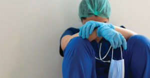 Stressed tired healthcare worker sitting on floor