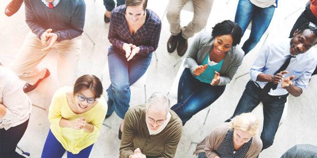 Group of employees seated at a meeting clapping